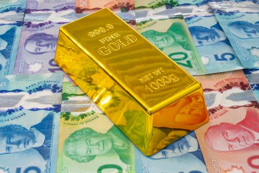 Calgary, Alberta, Canada. April 10, 2021. A Gold Bar or Golden Brick Bullion on Canadian Bills currency.