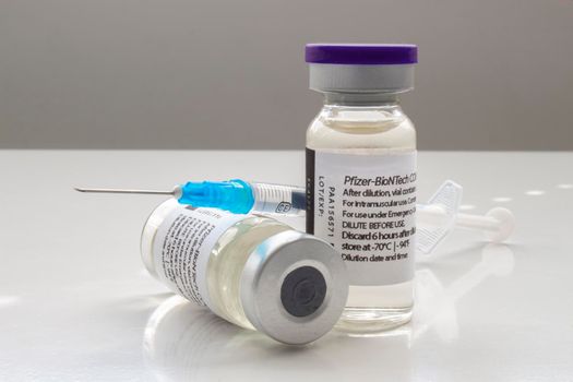 Calgary, Alberta. Canada. April 02, 2021. A couple of Pfizer Covid-19 vaccine vials with a syringe