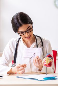 Woman doctor showing heart model to students