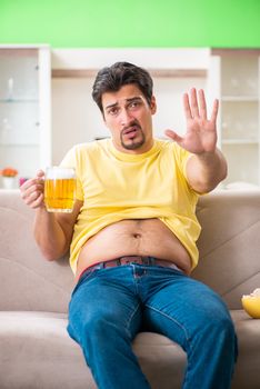 Fat obese man holding beer in dieting concept