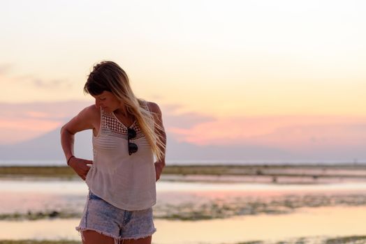 Young blonde girl on Gili Trawangan beach in Lombik, Indonesia at sunset time.