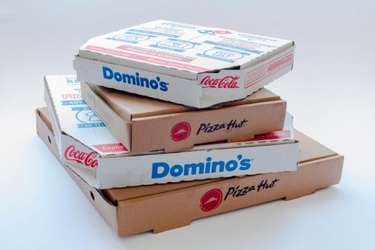 Calgary, Alberta, Canada. Feb 15, 2021. Pizza Hut and Domino's Pizza boxes on top of each other on a clear background.