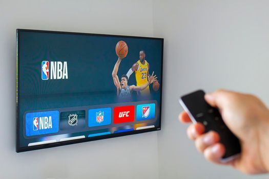 Calgary, AB, Canada. June 11, 2020. A person using an apple tv remote using the NBA application. Concept watching American basketball.