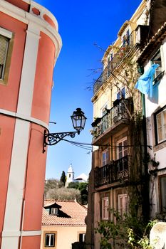 Old colorful and beautiful facades with vintage streetlight in Lisbon streets in Spring. Clothesline in the facade with hanging clothes
