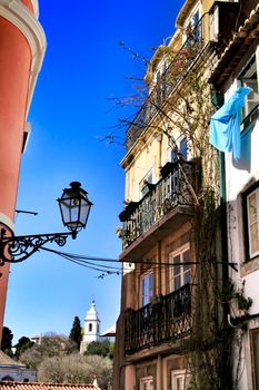 Old colorful and beautiful facades with vintage streetlight in Lisbon streets in Spring. Clothesline in the facade with hanging clothes