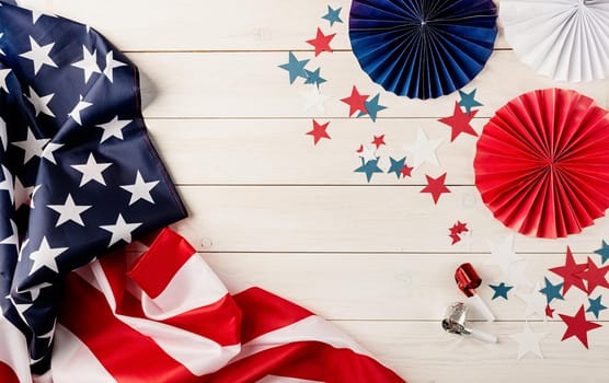 Decorations for 4th July, Independence Day USA. Paper fans, national flag, stars and noisemakers on white wooden background. Copy space, flat lay