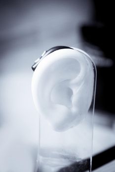 Plastic ear with modern hearing aid. No people