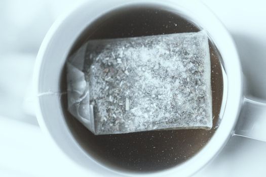 White cup with infusion and tea bag. No people