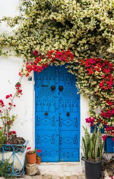 Blue door with traditional ornament as symbol of Sidi Bou Said and flowers