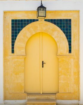 Yellow door with ornament and lantern from Sidi Bou Said in Tunisia. Culture of Tunisia