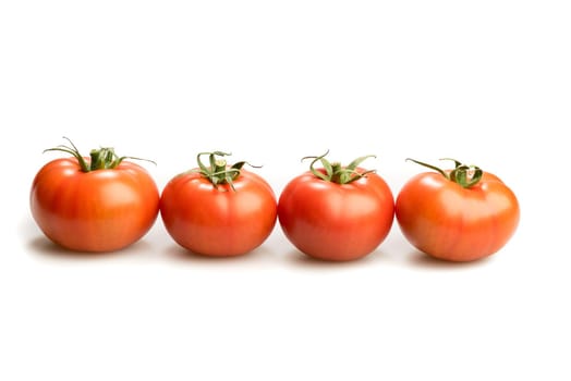 Four realistic looking fresh red tomatoes lying in a line isolated in a white background
