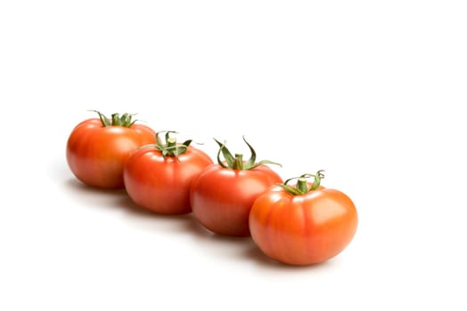 Four realistic looking fresh red tomatoes lying in a skew line isolated in a white background