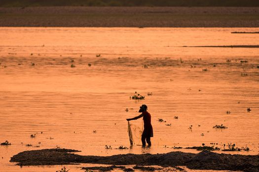 Asian Woman fishing in the river. silhouette at sunset. Village life in Asia