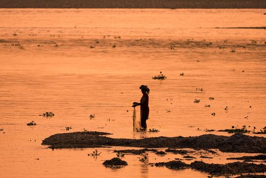 Asian Woman fishing in the river. silhouette at sunset. Village life in Asia