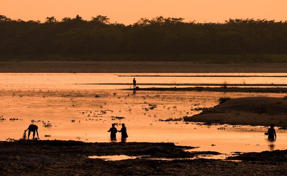 Asian Women fishing in the river. silhouette at sunset. Village life in Asia