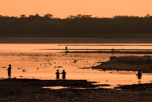 Asian Women fishing in the river. silhouette at sunset. Village life in Asia