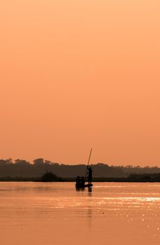 Men in a boat on a river silhouette with sunset light