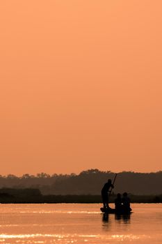 Men in a boat on a river silhouette with sunset light