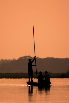 Men in a boat on a river silhouette with sunset light