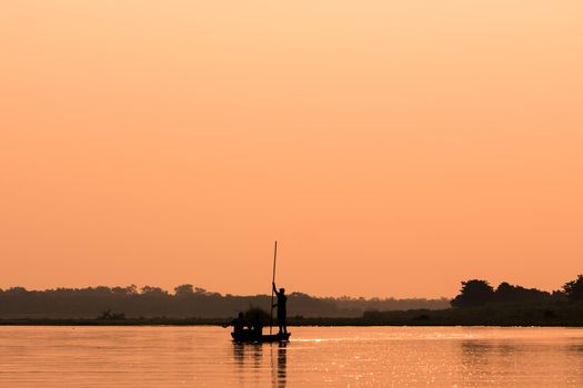 Men in a boat on a river silhouette with sunset light