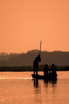 Blurred Men in a boat on a river silhouette with sunset light. Artistic blur