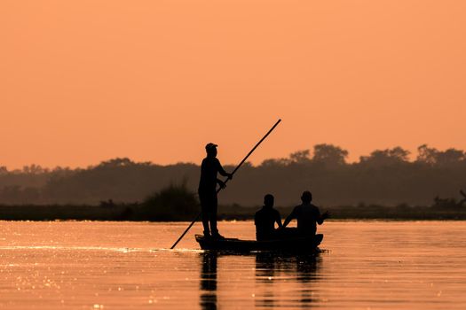 Men in a boat on a river silhouette with sunset light