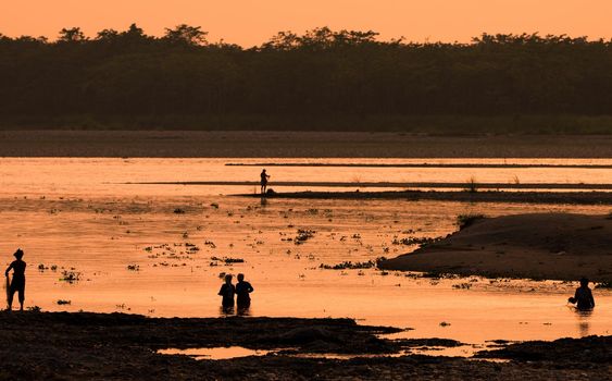 Asian Women fishing in the river. silhouette at sunset. Village life in Asia