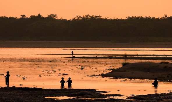 Asian Women fishing in the river. silhouette at sunset. Village life in Asia