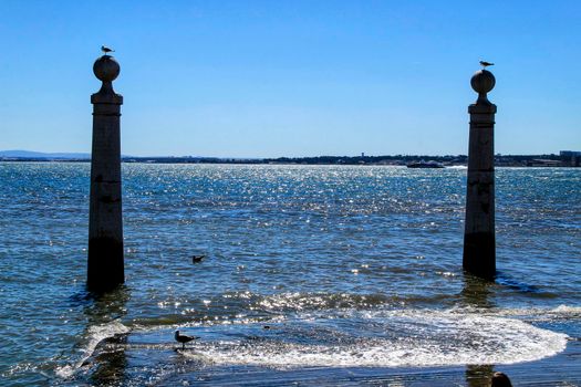 Pillars of Do Comercio square on the banks of the Tagus River in Lisbon in a sunny day of spring. Segulls on the top.