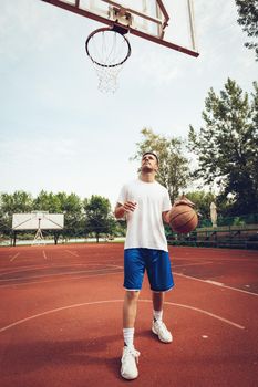 Young man is training basketball on street court. He is ready to shoot.