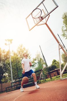 Young man training basketball on street court. He is ready to shoot.