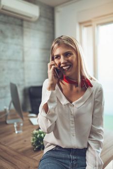 Young successful female entrepreneur talking on a smart phone at the office.