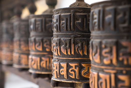 Buddhist prayer wheels in row with artistic shallow DOF in Nepal