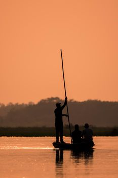 Men in a boat on a river silhouette with sunset light