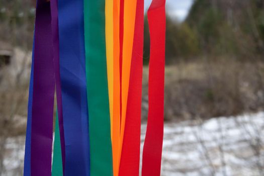 Bright rainbow ribbons on the background of a spring river.Carnival ribbons. LGBT symbol.