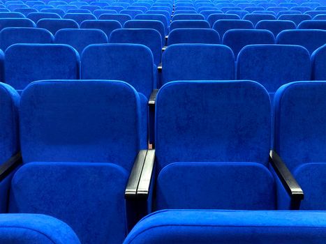 Rows of blue chairs in an empty concert hall.