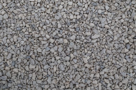 Dry white limestone ballast flat full frame background. Small gray dusty broken macadam stones texture. Viiew from above.