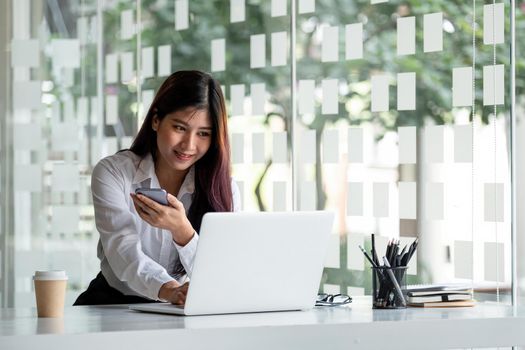 Woman using laptop computer and smartphone for online education at home.