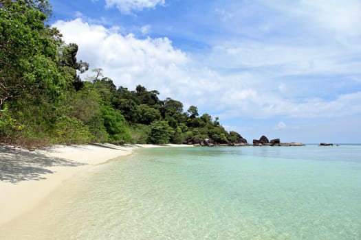 Sand, blue water, green trees on the island. And a blue sky.