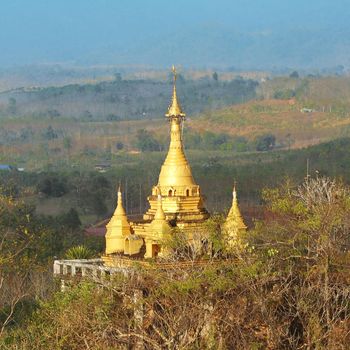 Golden stupa on a hilltop in the countryside. Kanchanaburi, Thailand