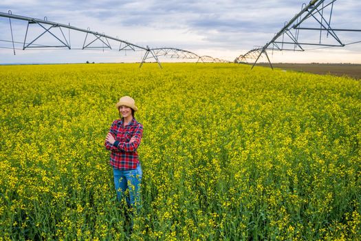 Proud female farmer is standing in her rapeseed field.