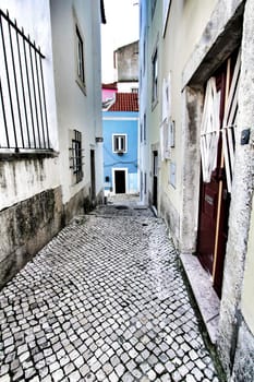 Narrow and colorful streets with majestic facades, windows and balconies of Lisbon city in Portugal in a cloudy day