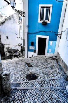 Narrow and colorful streets with majestic facades, windows and balconies of Lisbon city in Portugal in a cloudy day