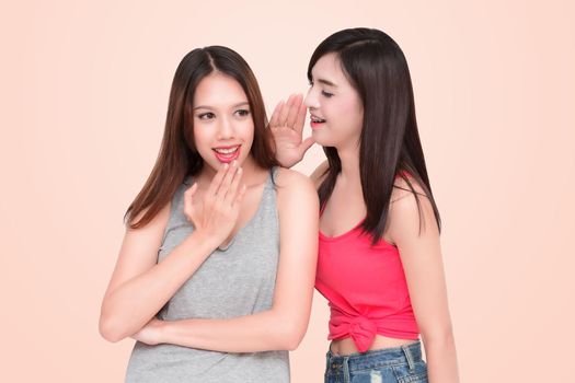 Two women whispering and smiling