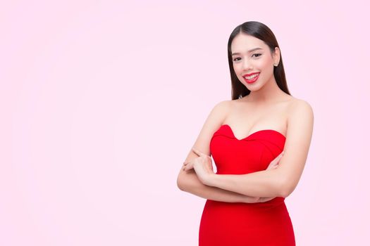 Beautiful sexy young woman in a red dress on a pink background