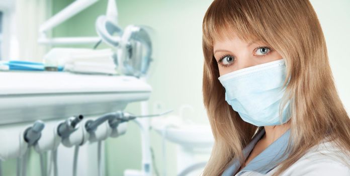 Female dentist in protective mask and whitecoat