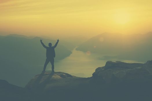 Young happy tourist on top of a mountain enjoying valley view before sunset.