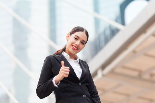 Confident young businesswoman giving the thumbs up 