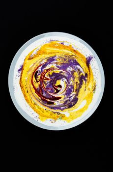 A plate with yellow paint and circular stains on a dark background.Abstract art. Search for material for art work.