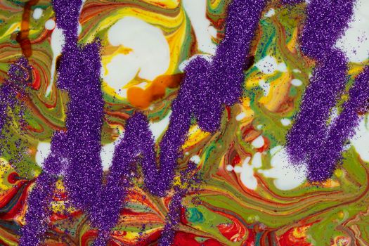 A background made up of many textures, shapes and materials. Purple sparkles are scattered on a multicolored acrylic background.